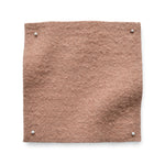 Wool boucle swatch pinned in all corners in soft pink.