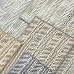 Close up of broadloom carpets with striated herringbone weave in a range of cool neutral colors. 