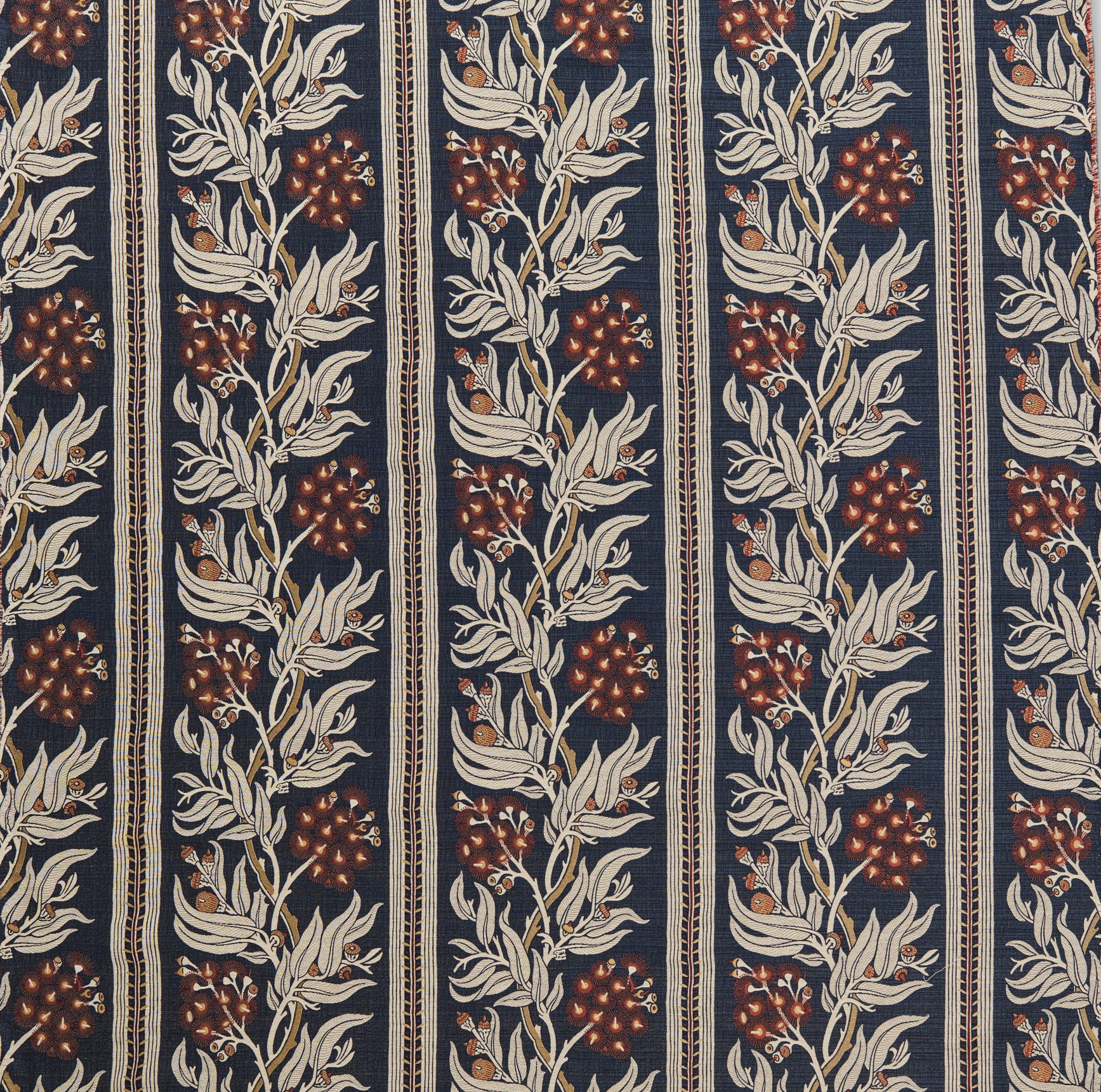 Woven performance fabric in a botanical branch and stripe design in beige, tan and red on a navy blue field. 