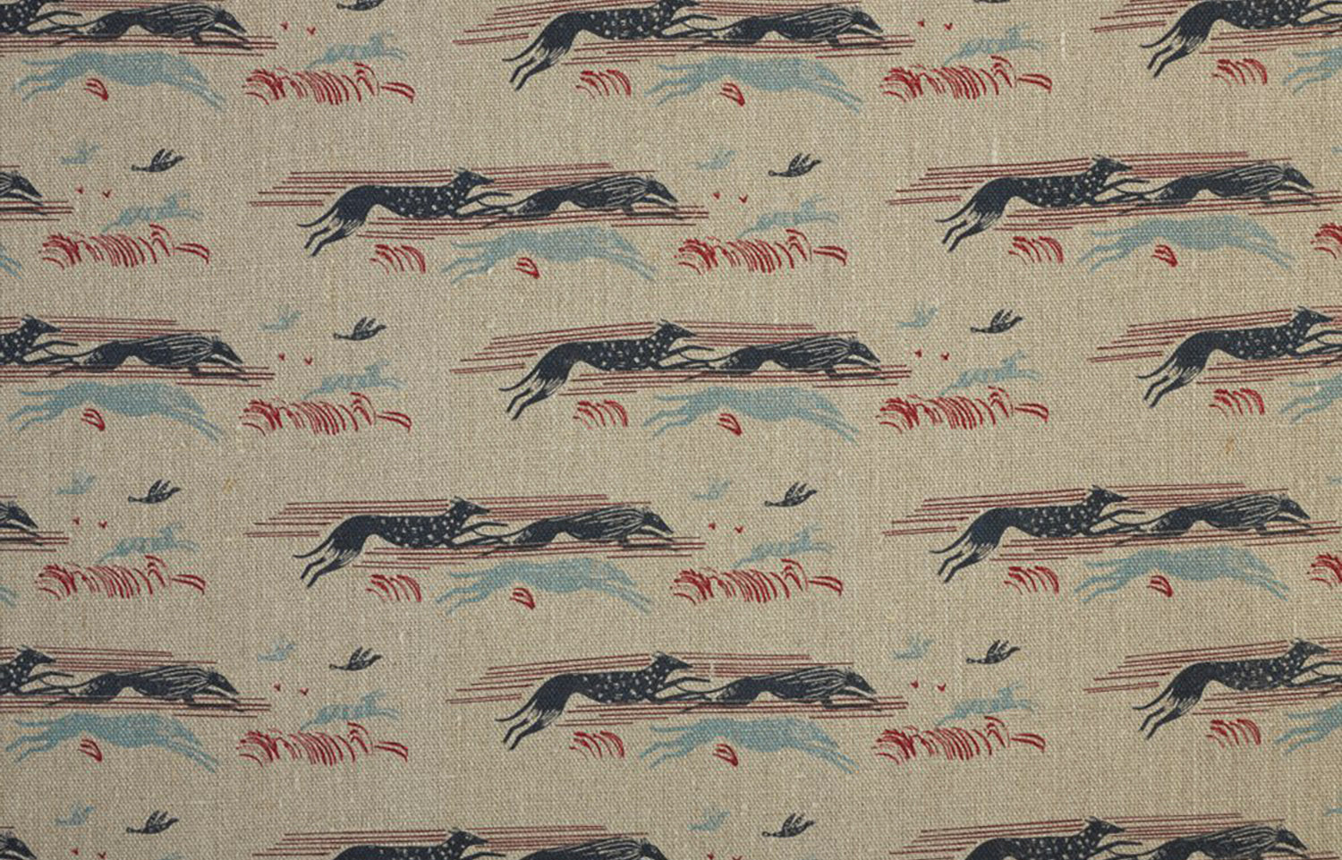 Detail of fabric in a running whippet print in shades of navy, blue and red on a tan field.