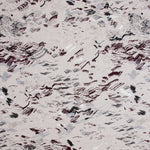 Detail of fabric in a painterly seaside print in shades of gray and maroon on a tan field.