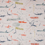 Detail of fabric in a painterly tree branch print in shades of blue, navy and red on a greige field.