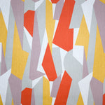 Detail of fabric in an abstract geometric print in yellow, red, white and gray.