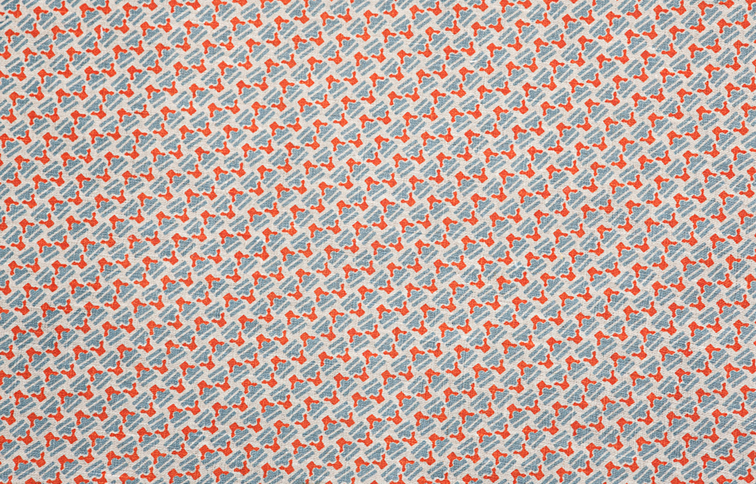 Detail of fabric in a dense geometric print in red, blue and cream.