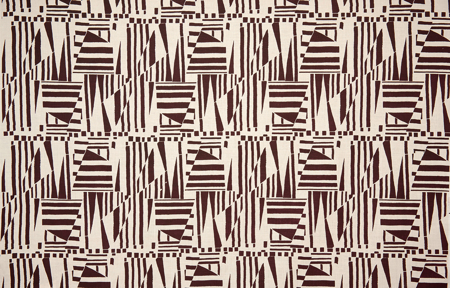 Detail of fabric in a dense geometric print in brown on a cream field.