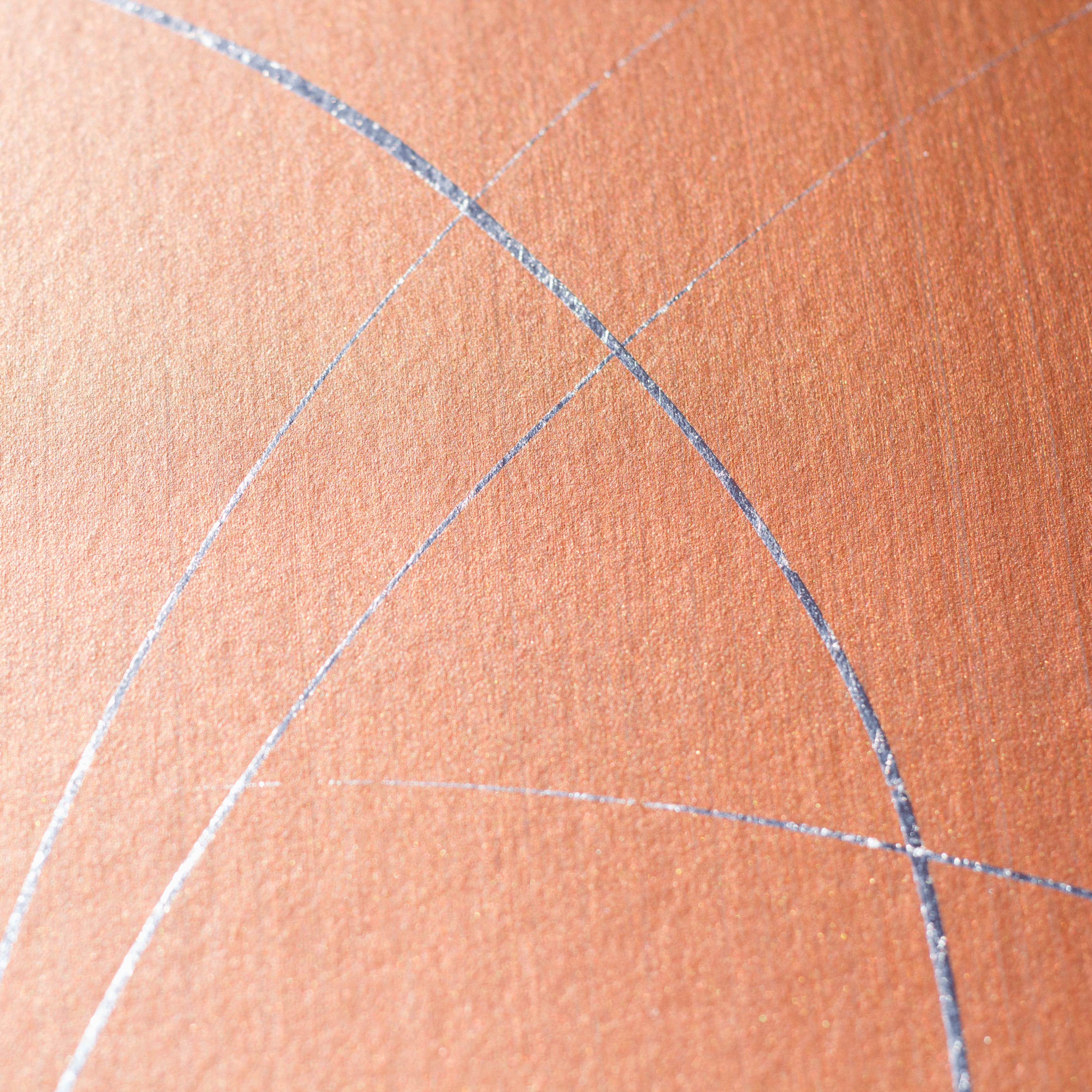 Wide-angle shot of wallpaper in an abstract curved line pattern in metallic silver on an orange field.