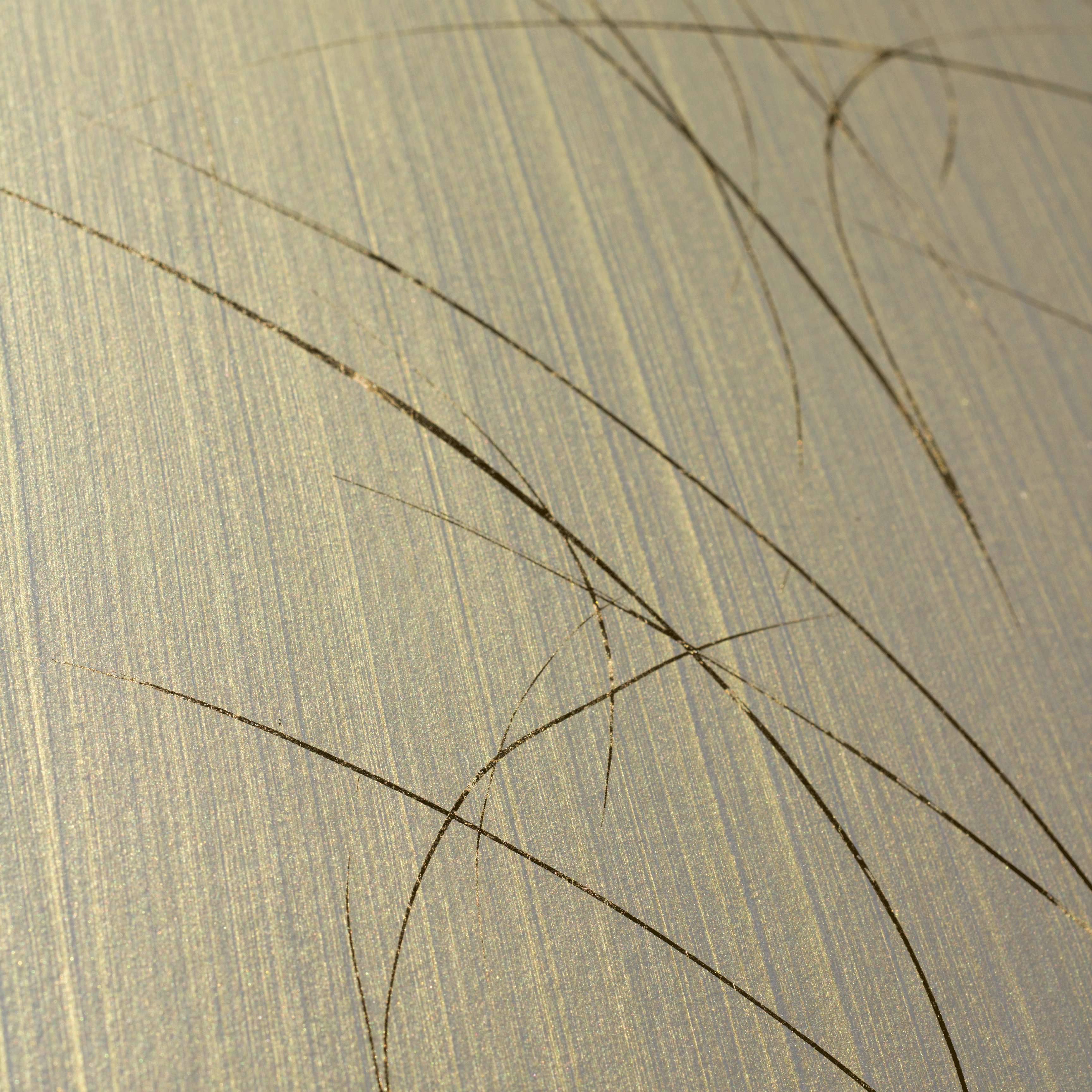 Wide-angle shot of wallpaper in an abstract curved line pattern in gold on a metallic field.