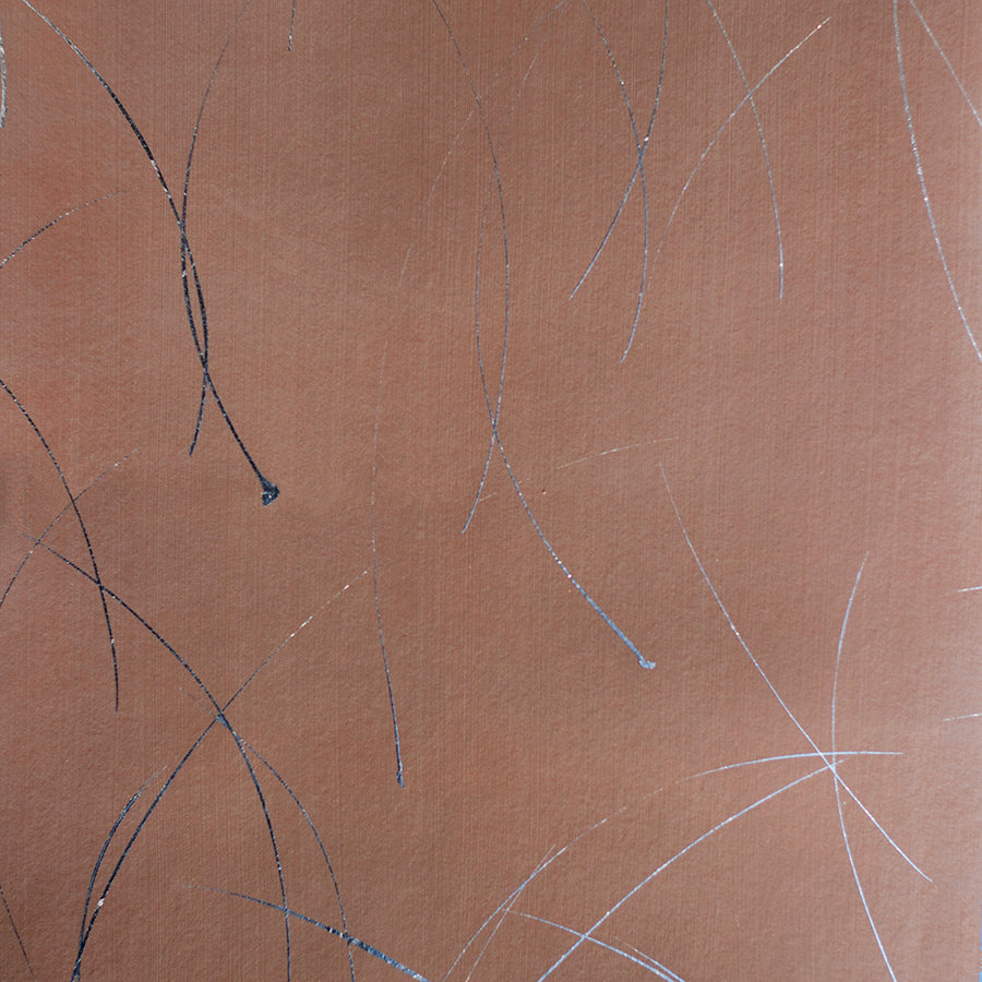 Detail of a wallpaper in an elongated paint splatter pattern in metallic navy on a rust field.