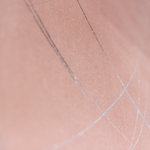 Wide-angle shot of wallpaper in an abstract curved line pattern in silver on a pink field.