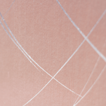 Wide-angle shot of wallpaper in an abstract curved line pattern in silver on a pink field.