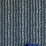 A vase of flowers stands in front of a wall covered in a repeating striped circular print in cream on a navy field.