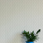 A vase of flowers stands in front of a wall papered in a playful curvy stripe print in gray on a light gray field.