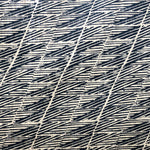 Detail of fabric in a textural geometric stripe in navy on a tan field.