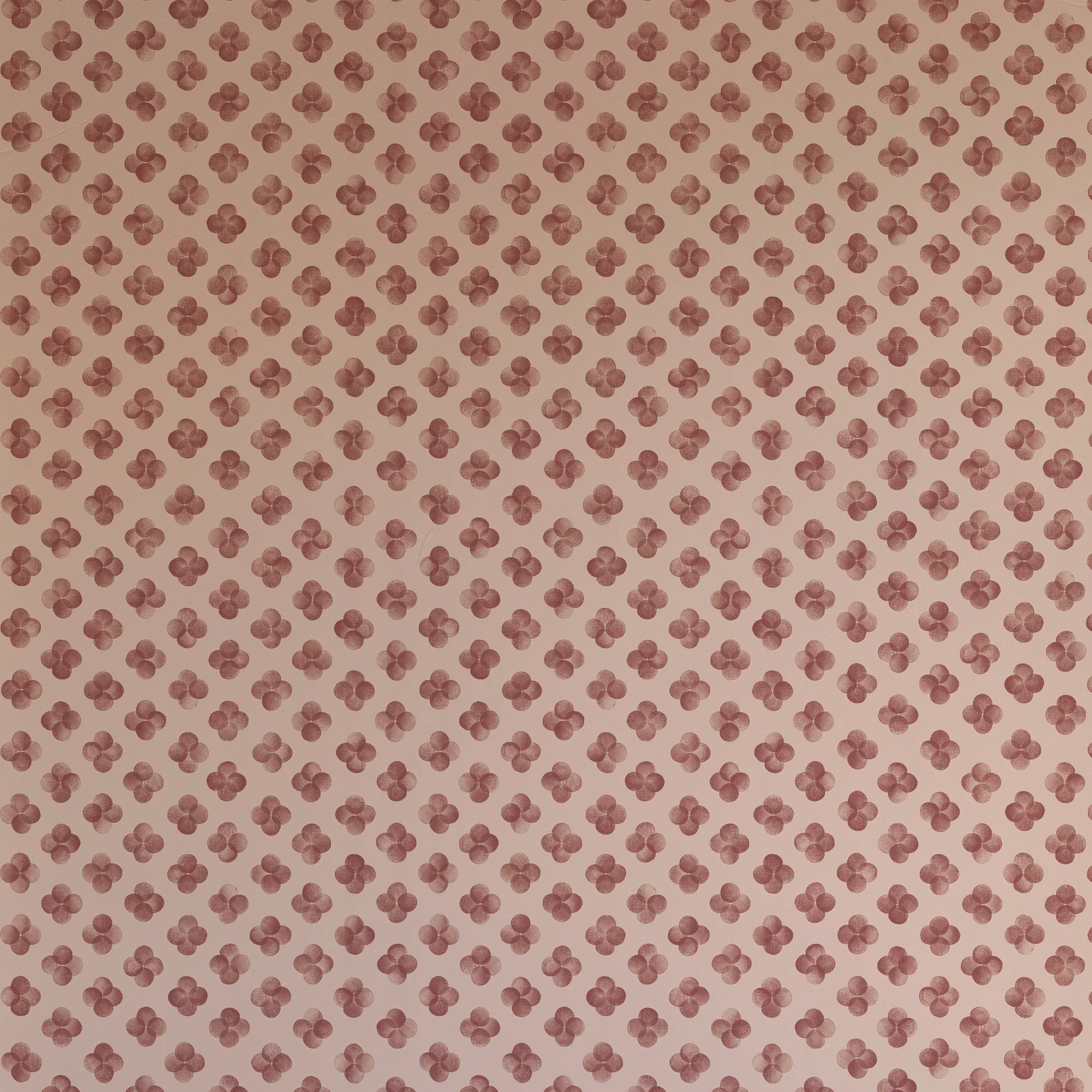 Detail of wallpaper in a minimalist quatrefoil pattern in red on a cream field.