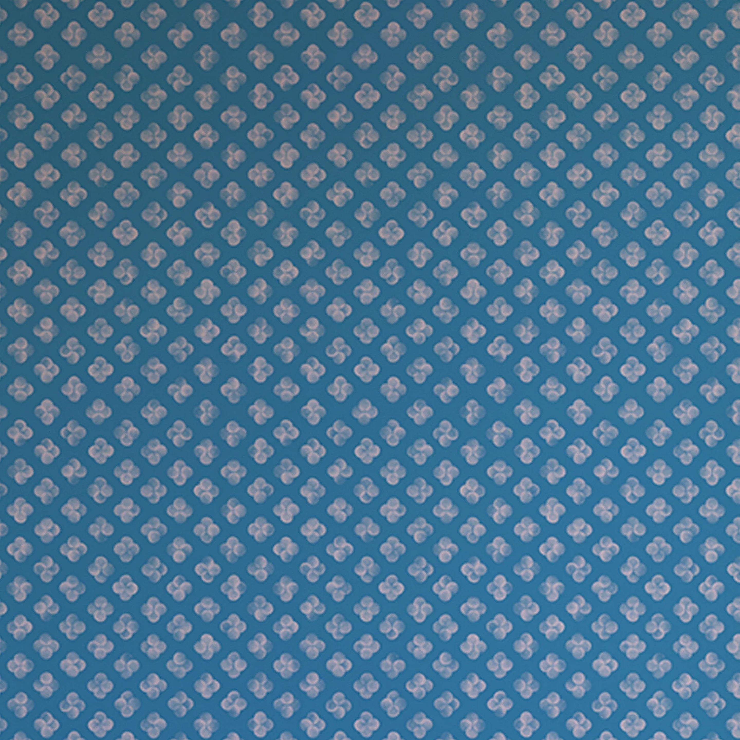 Detail of wallpaper in a minimalist quatrefoil pattern in light pink on a blue field.