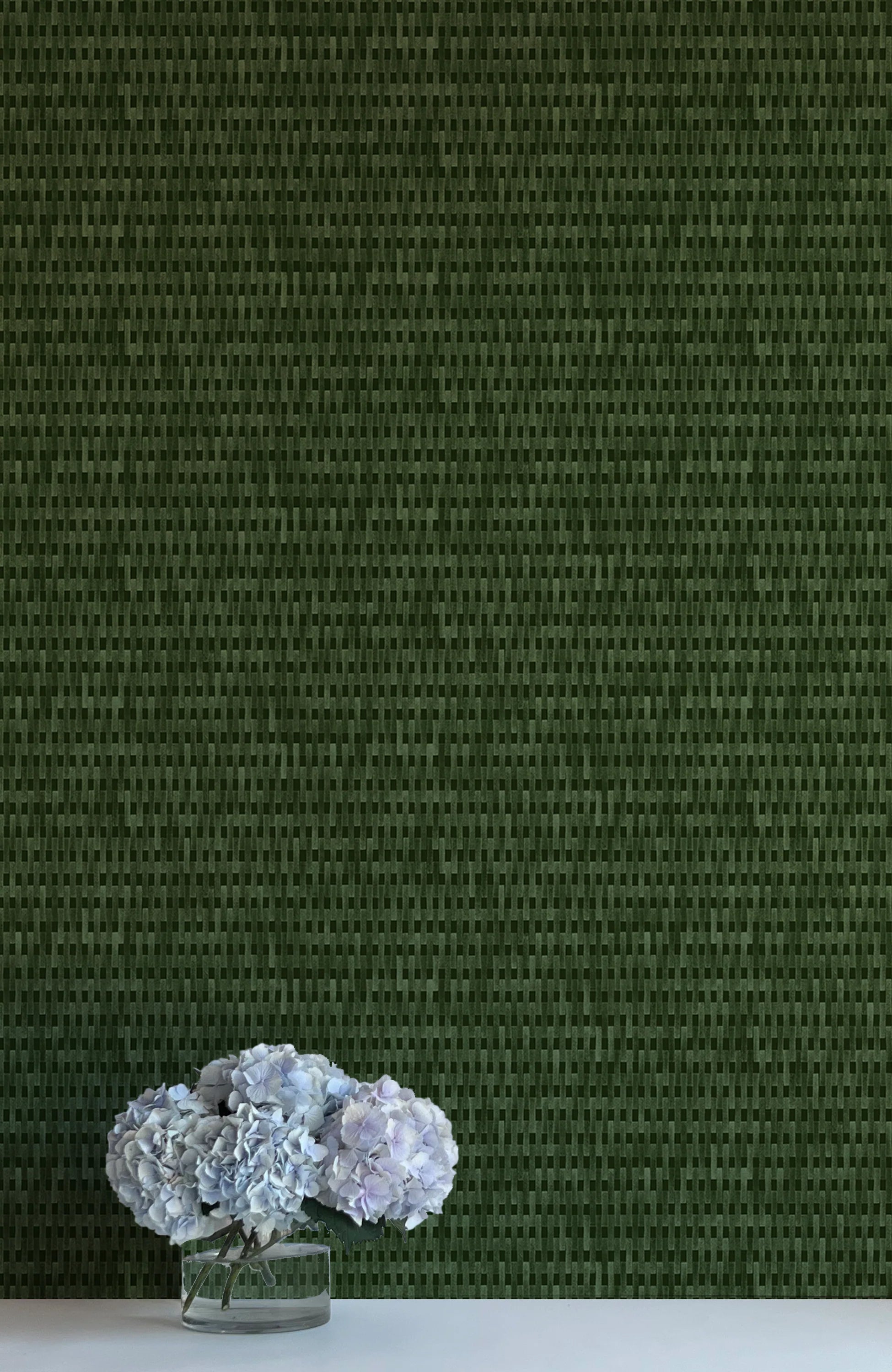 A vase of flowers stands in front of a wall covered in a textural grid print in shades of green.