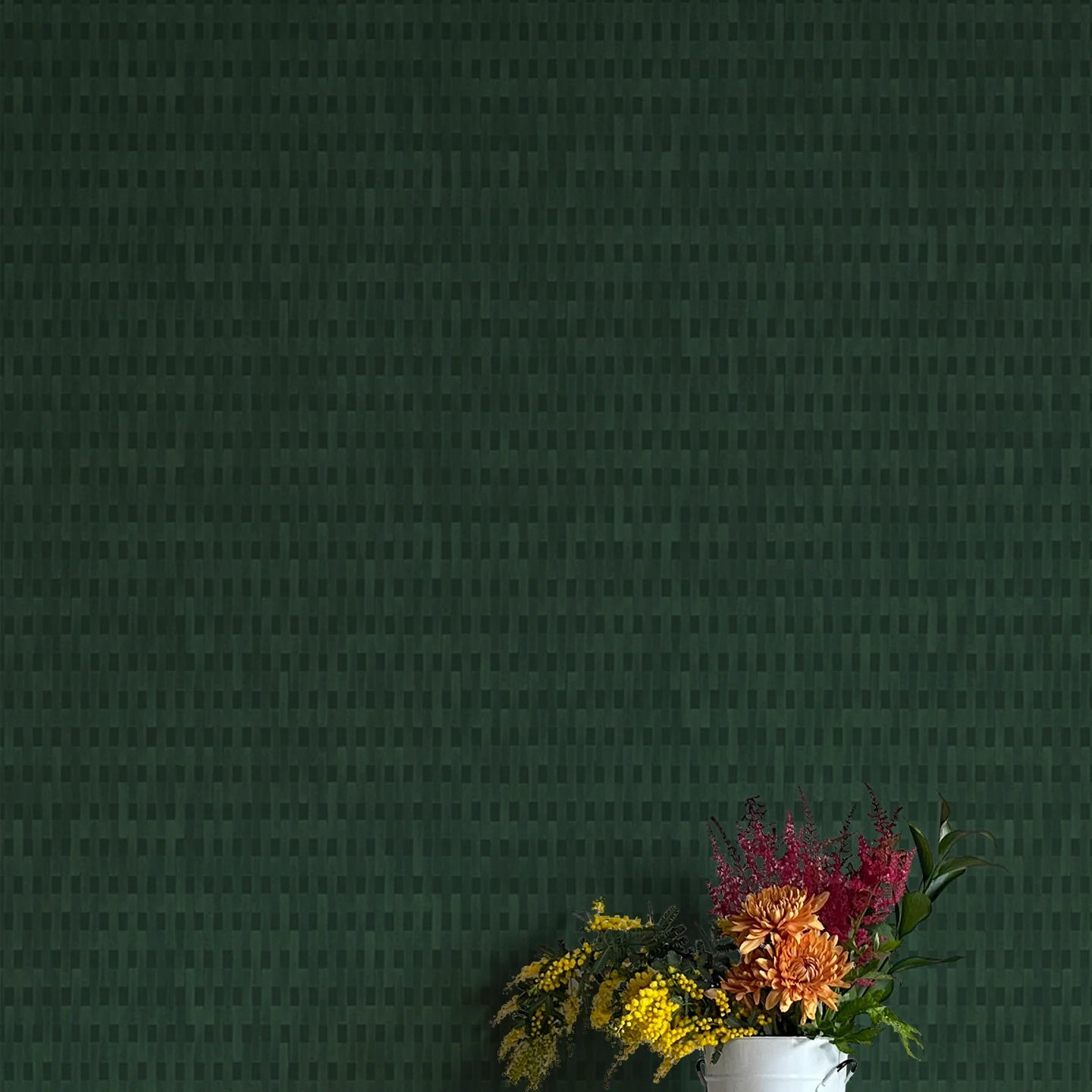 A vase of flowers stands in front of a wall covered in a textural grid print in shades of dark green.