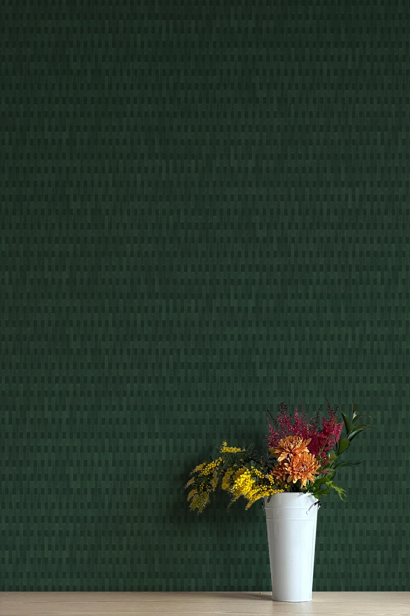 A vase of flowers stands in front of a wall covered in a textural grid print in shades of dark green.