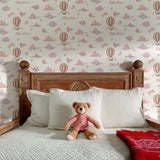 Bedroom with wooden headboard, white pillows, teddy bear, and hot air balloon wallpaper.