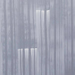 A table with a vase of buds stands in front of a wall papered in mottled blue and gold.