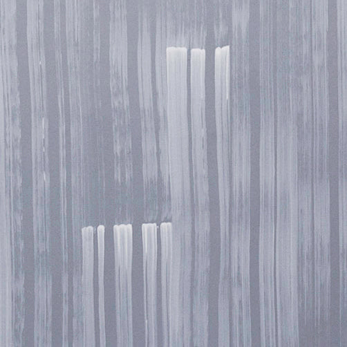 A table with a vase of buds stands in front of a wall papered in mottled blue and gold.