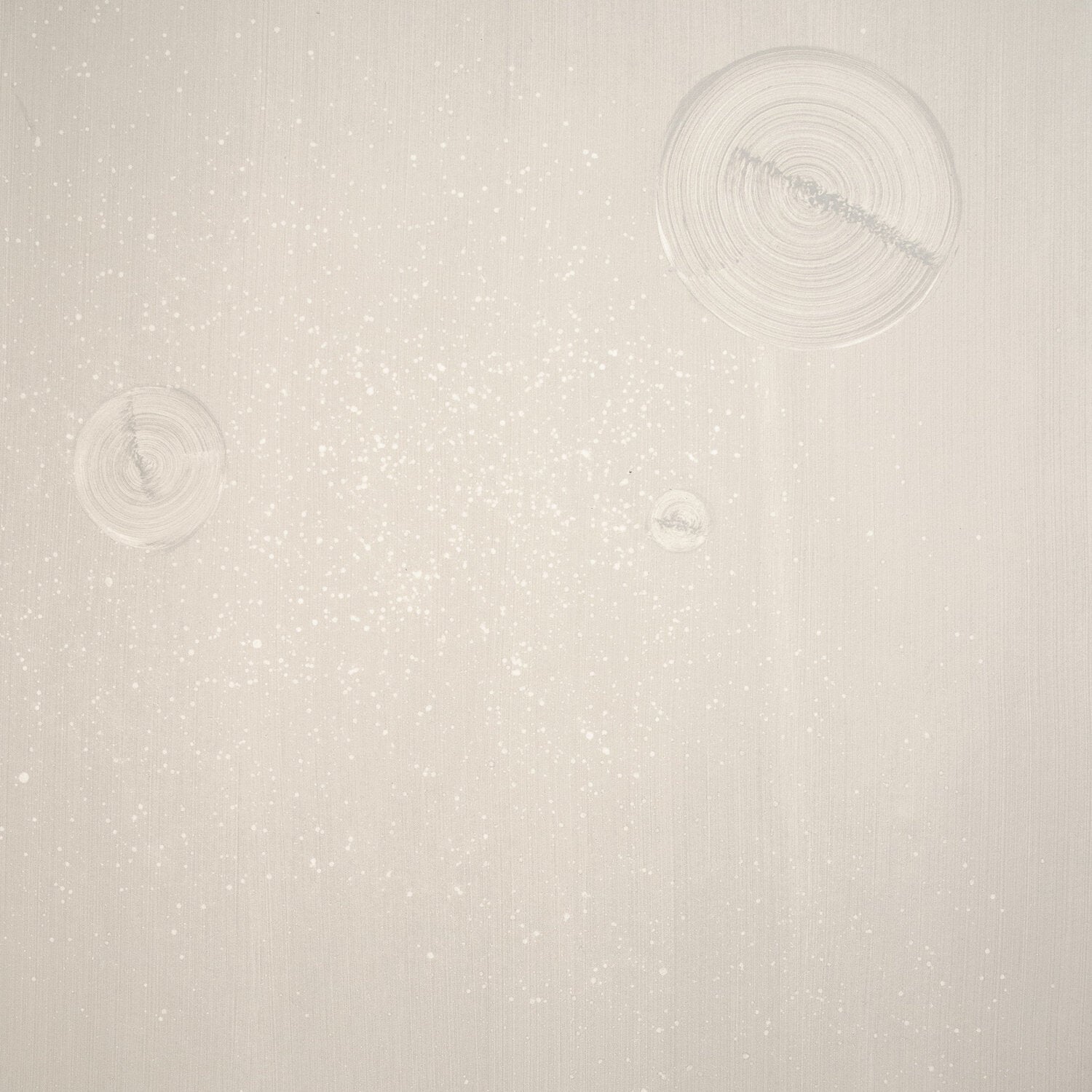 Detail of a wallpaper in a paint splatter print in metallic cream on a cream field.