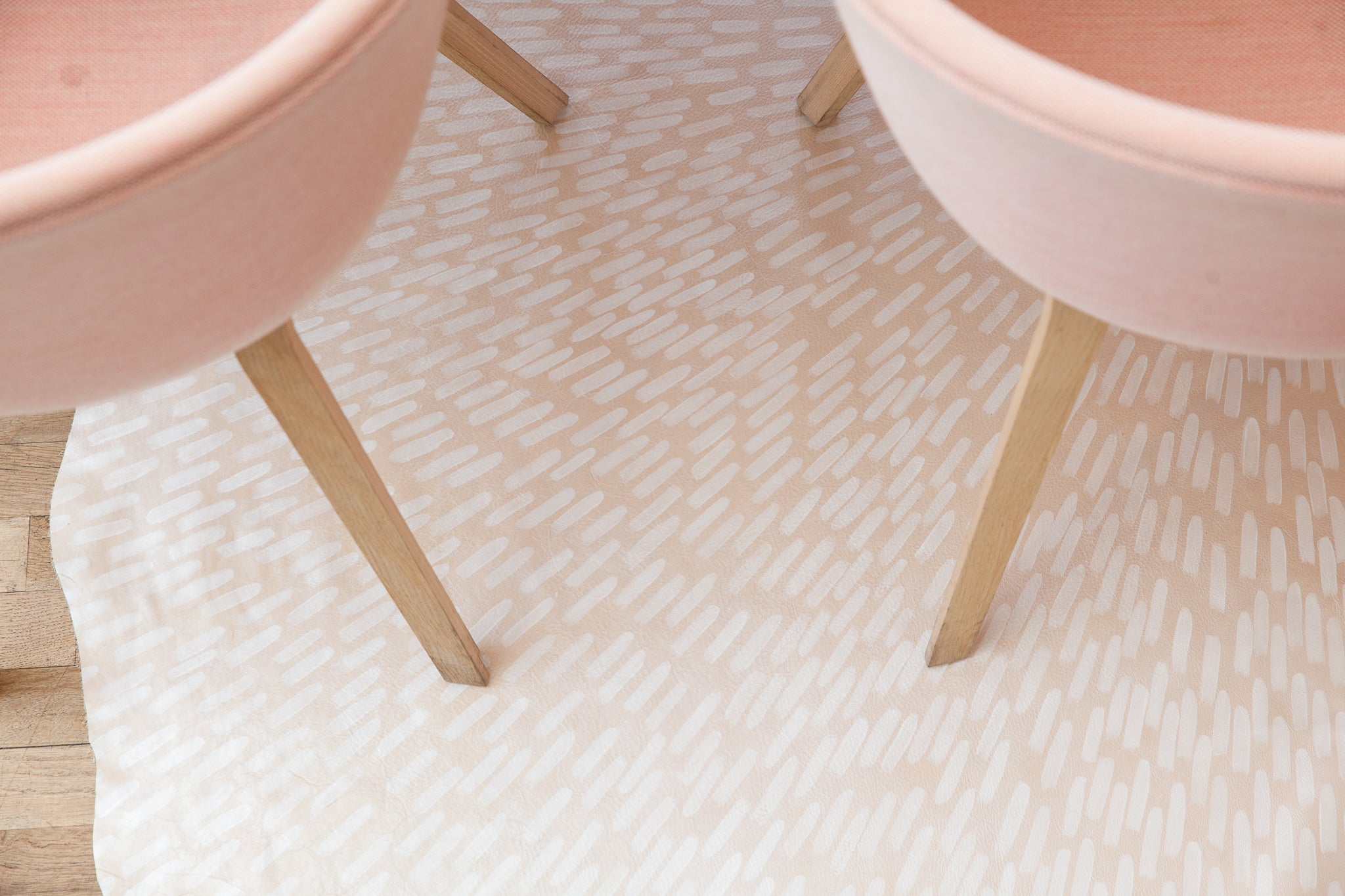 Two end tables stand on top of a cowhide rug in cream with a painterly starburst overlay in white.
