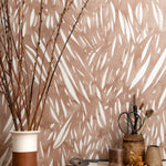 Mantle vignette with ceramic vases, branches and tailoring tools against wallpaper abstract leaf pattern in white on a terracotta watercolor field.