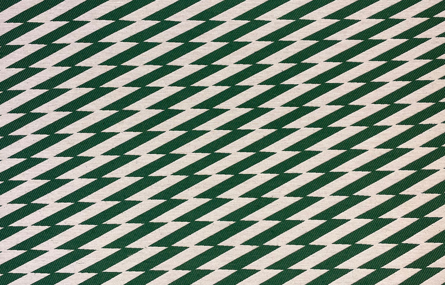 Detail of fabric in a zigzag stripe print in dark green on a cream field.