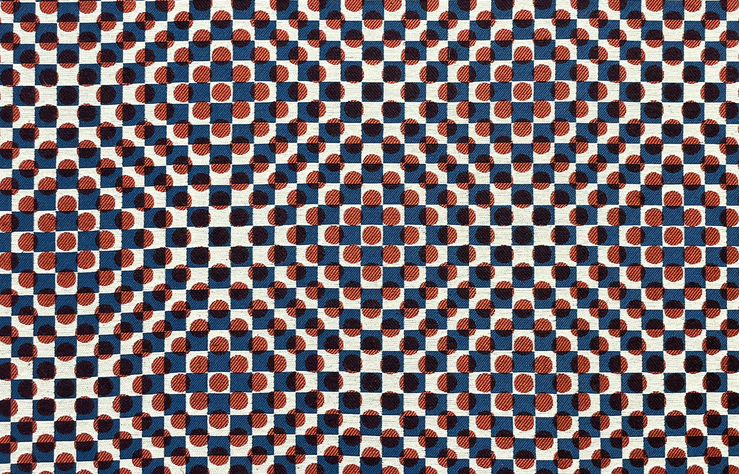 Detail of fabric in a geometric check and polka dot pattern in burnt orange, blue, cream and black.