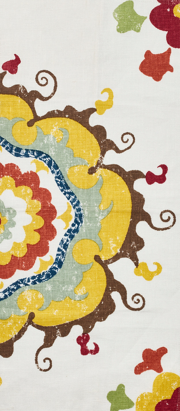 Detail of fabric in a floral paisley print in shades of blue, yellow, red and brown on a white field.