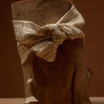 Wooden log with a checkered cloth tied around it against a brown background