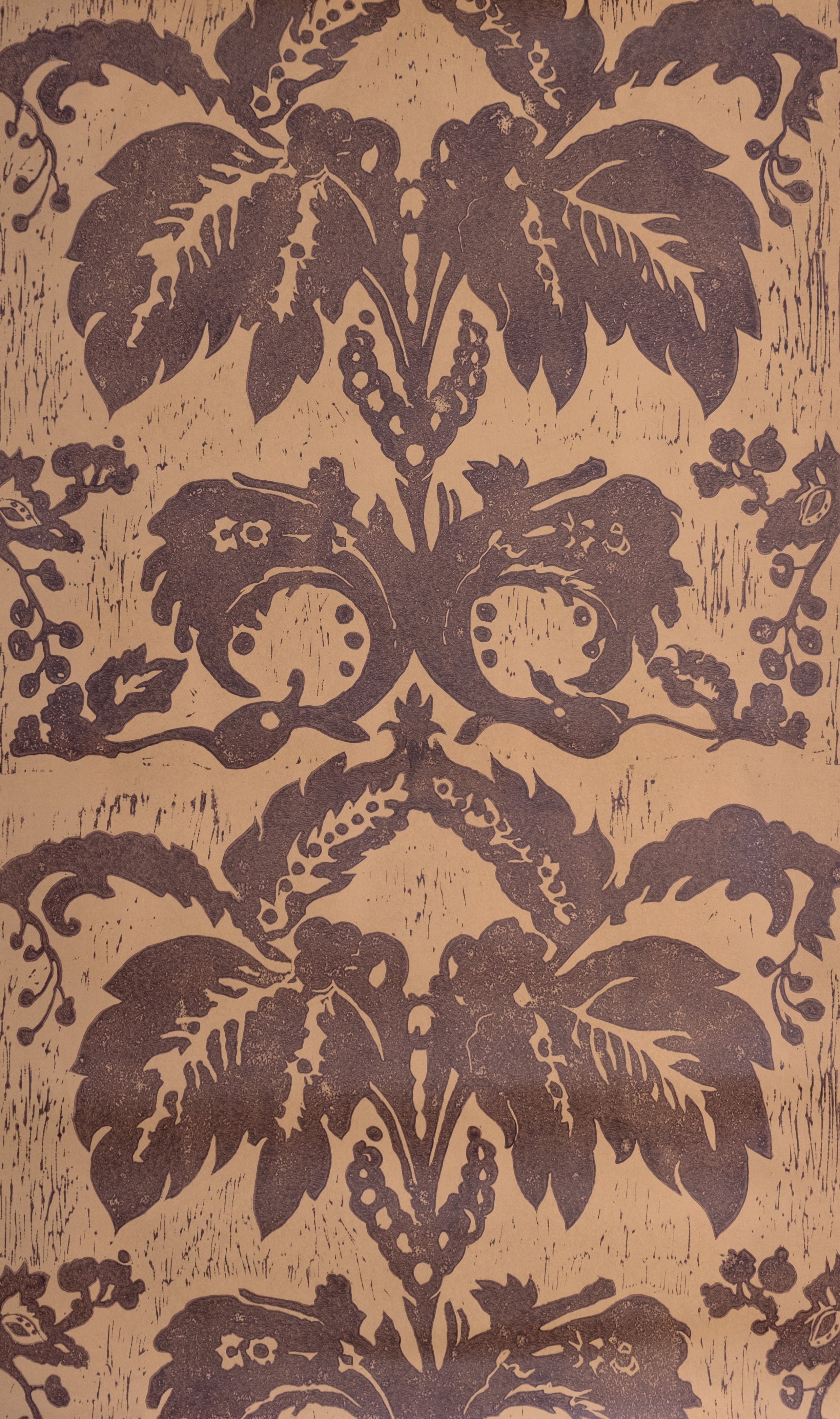 Detail of wallpaper in a repeating floral damask pattern in brown on a tan field.