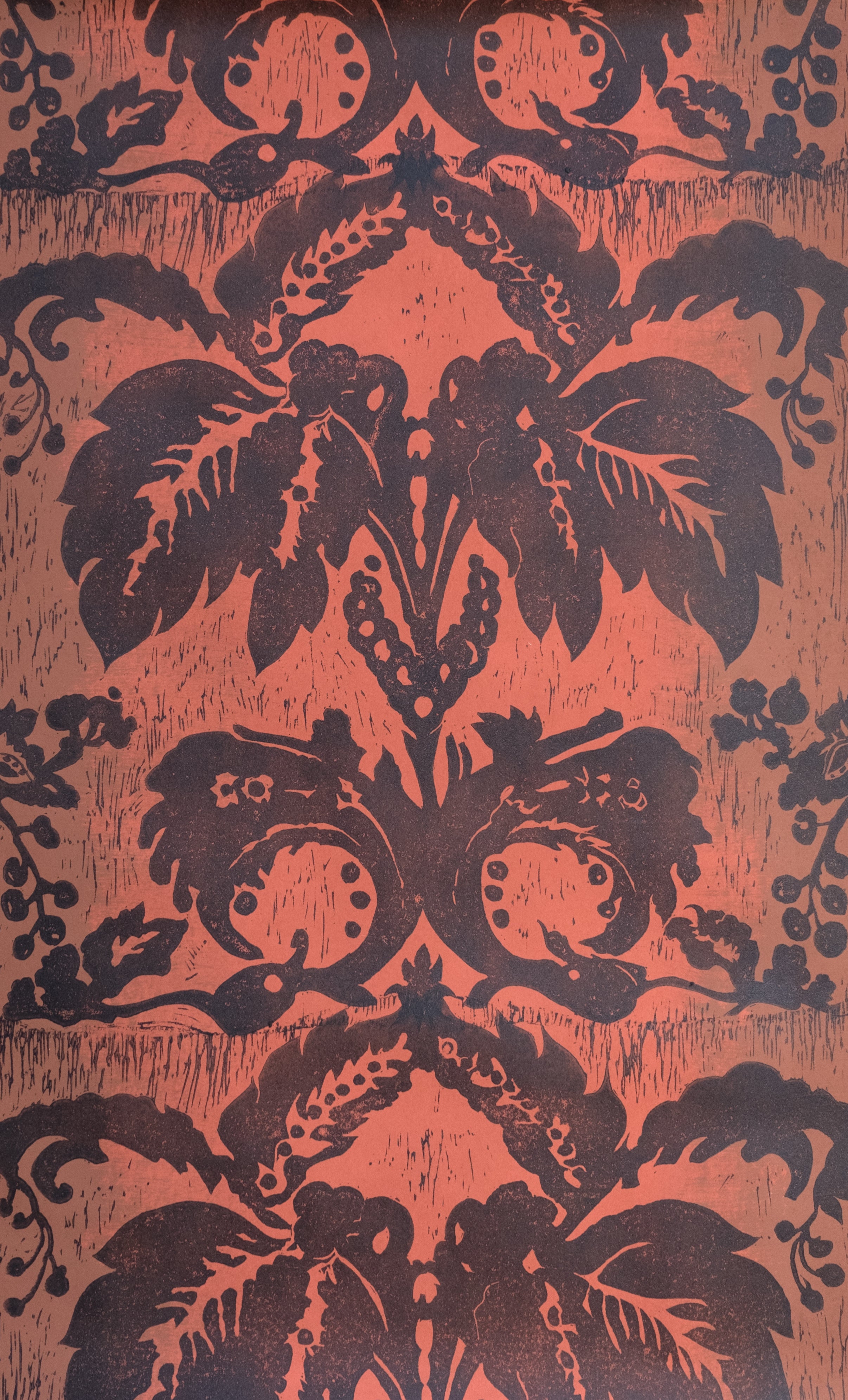 Detail of wallpaper in a repeating floral damask pattern in brown on a red field.