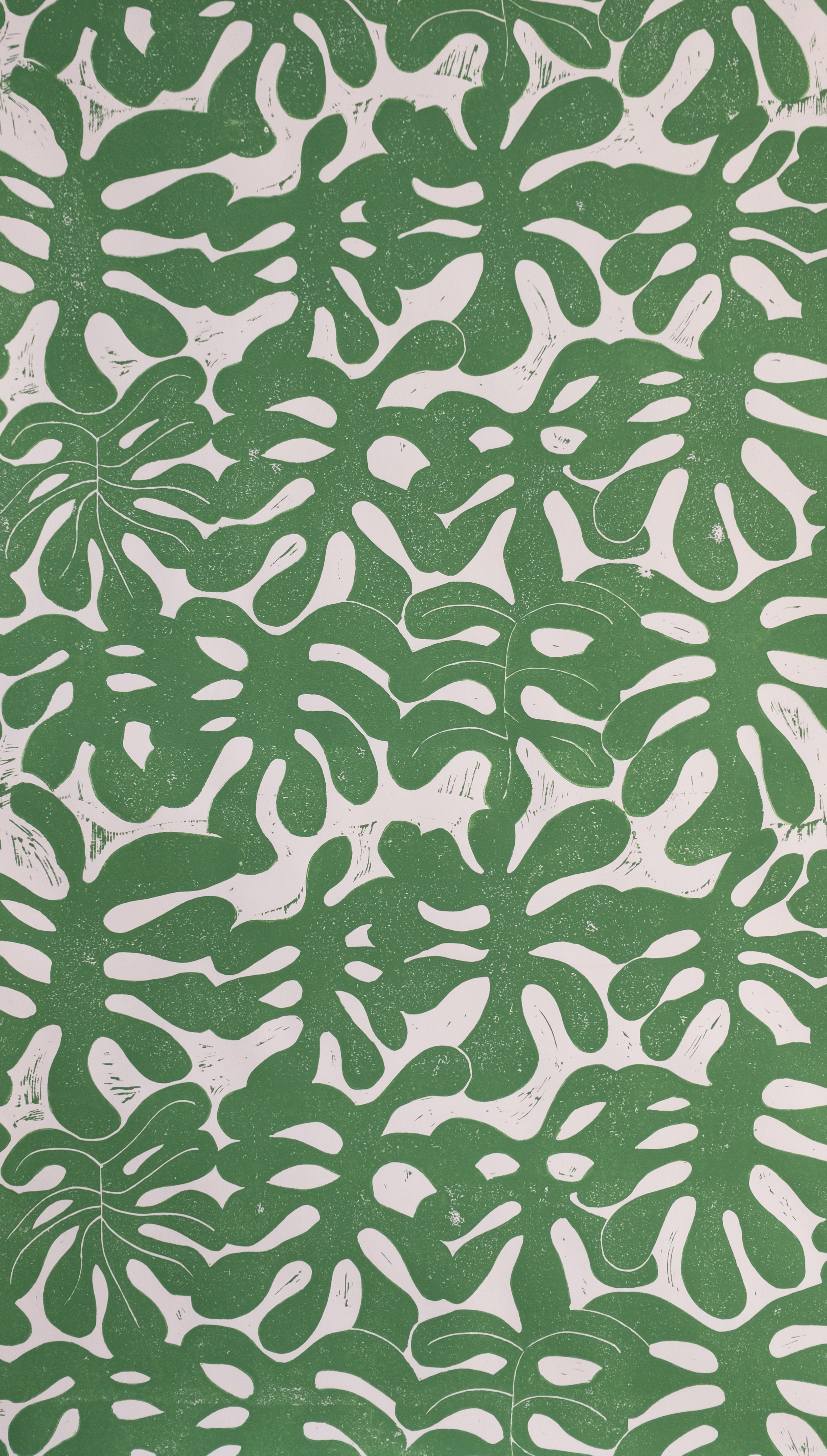 Detail of wallpaper in a playful repeating leaf print in green on a cream field.