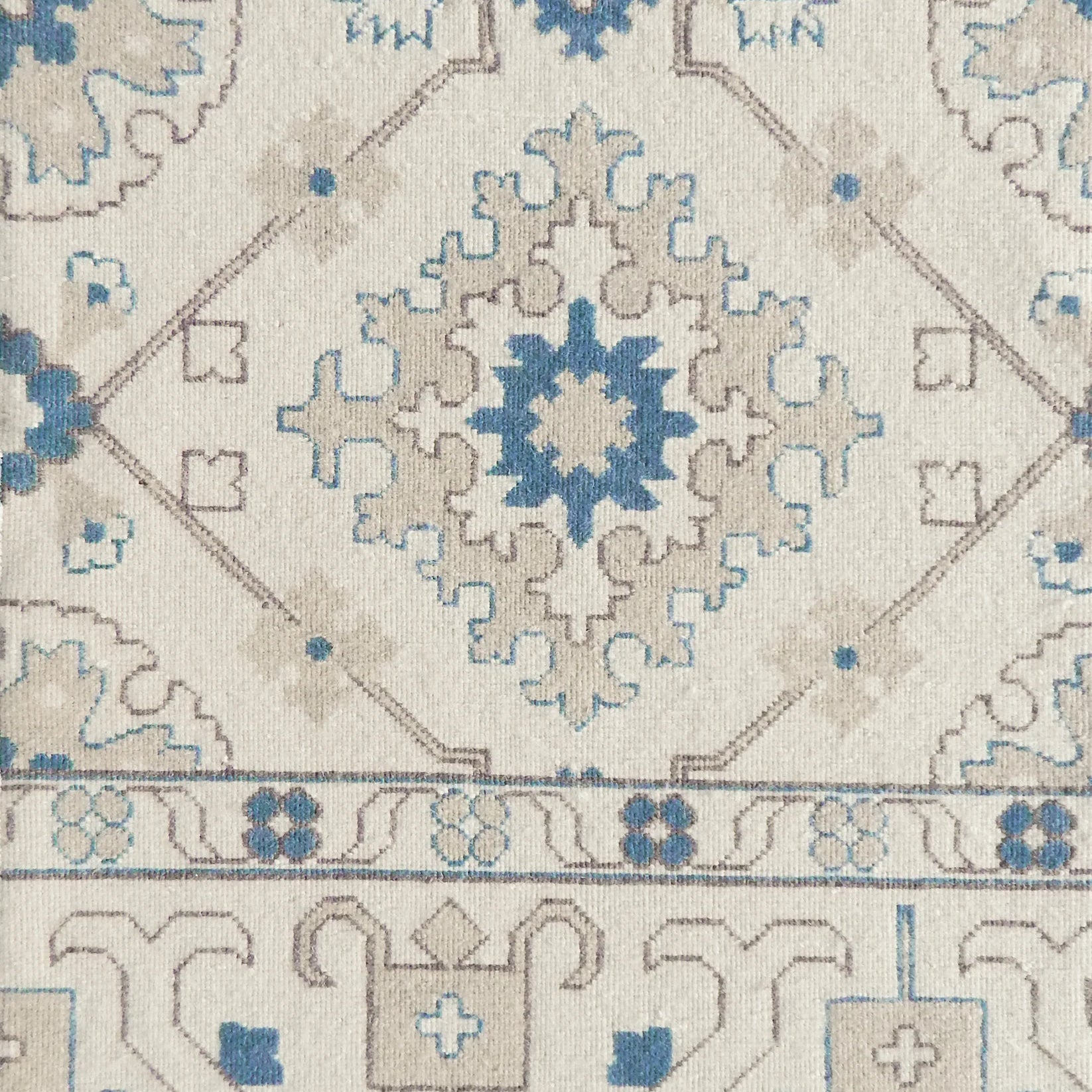Close-up of an ornate patterned rug with blue and beige colors