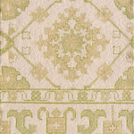 Detail of a handmade rug with with ornate green and cream design.