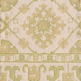 Detail of a handmade rug with with ornate green and cream design.