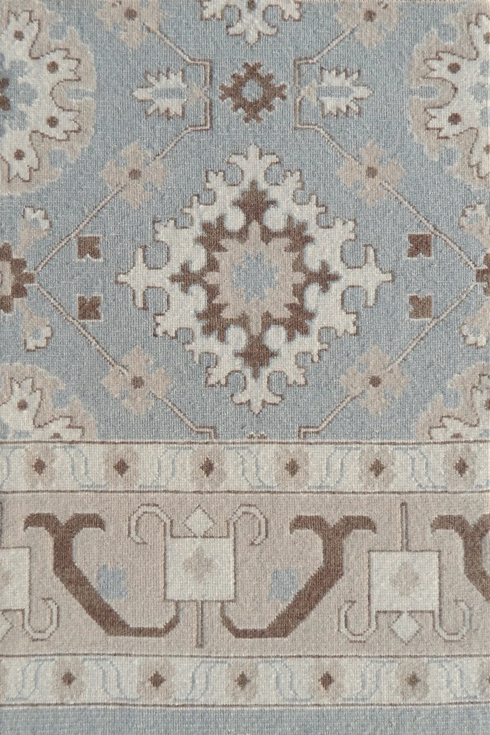Decorative rug with intricate pattern in blue and brown. 