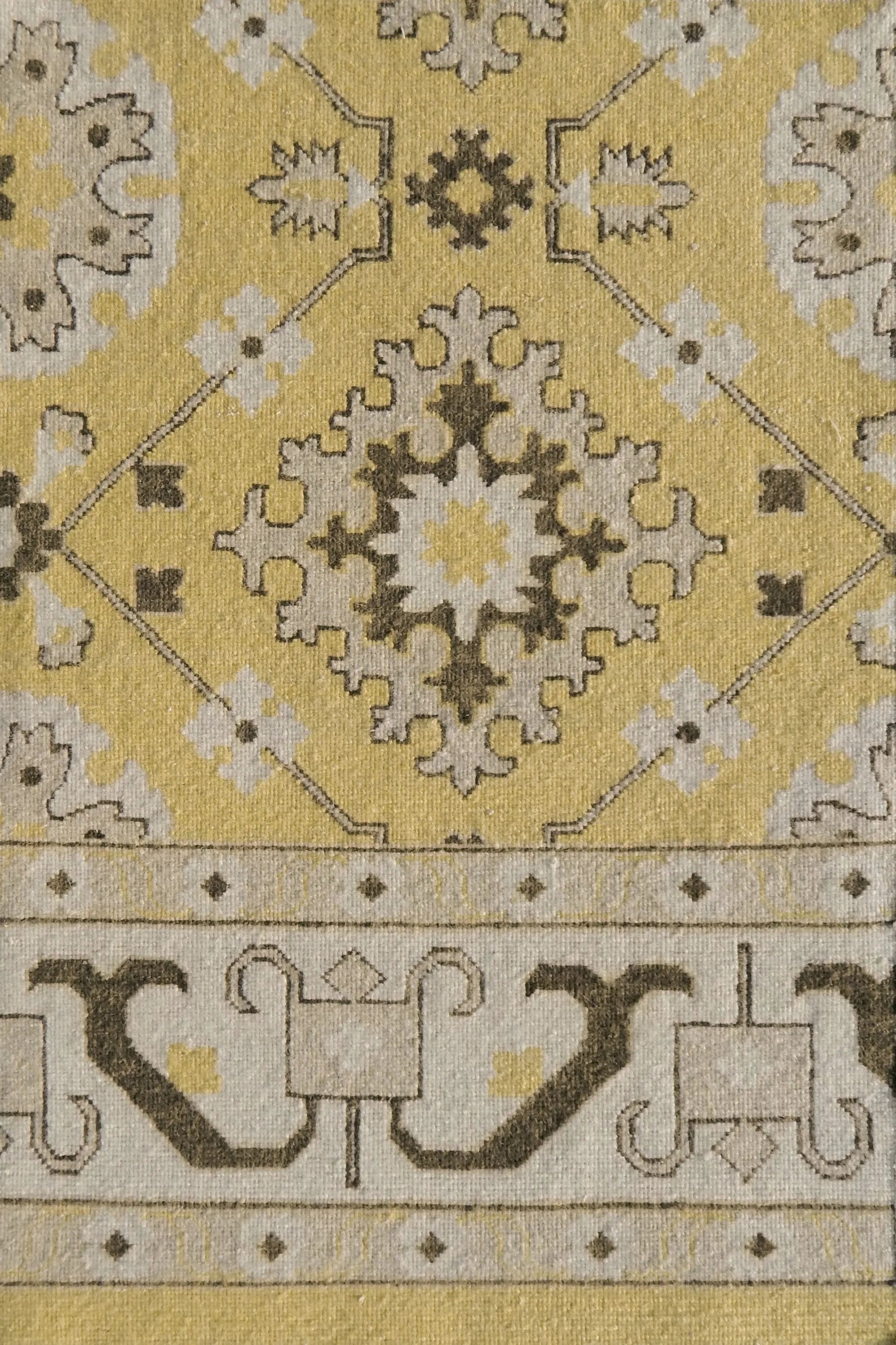 Close-up of a patterned rug with geometric design on a yellow background