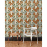 Chair and stool in front of a wall papered in a large, painterly vase and leaf print over a repeating diamond background in shades of blue and rust.