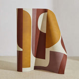 A curved partition stands on the ground, covered in a curvilinear geometric grid print in shades of mustard, purple, and cream.