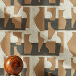 A sphere with marble base in front of a wall with a pattern of brown geometric vessel shapes over a white background with charcoal grey horizontal stripes.