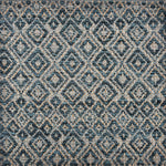 Handwoven rug sample in a radiating diamond pattern in shades of teal blue, grey, and tan. 