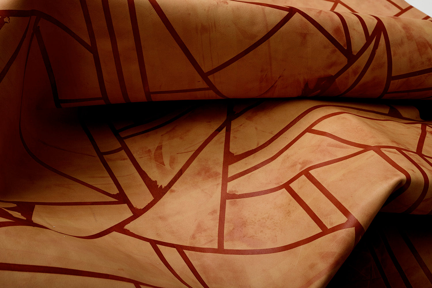 Close-up of a draped cowhide rug in mottled tan with a geometric brown overlay.
