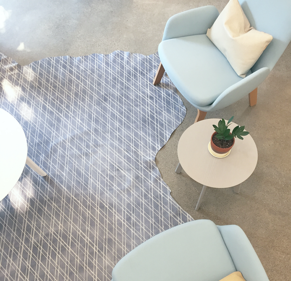 Overhead shot of a living space with a cowhide rug in gray with a white lattice overlay.