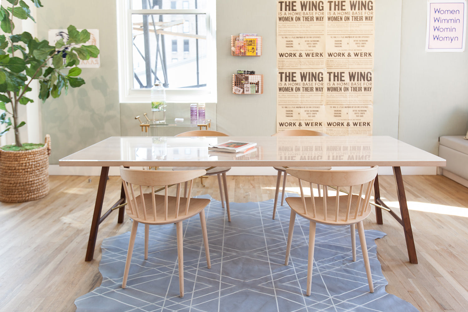 A cozy workspace with a table and chairs sitting on a cowhide rug with a geometric overlay.