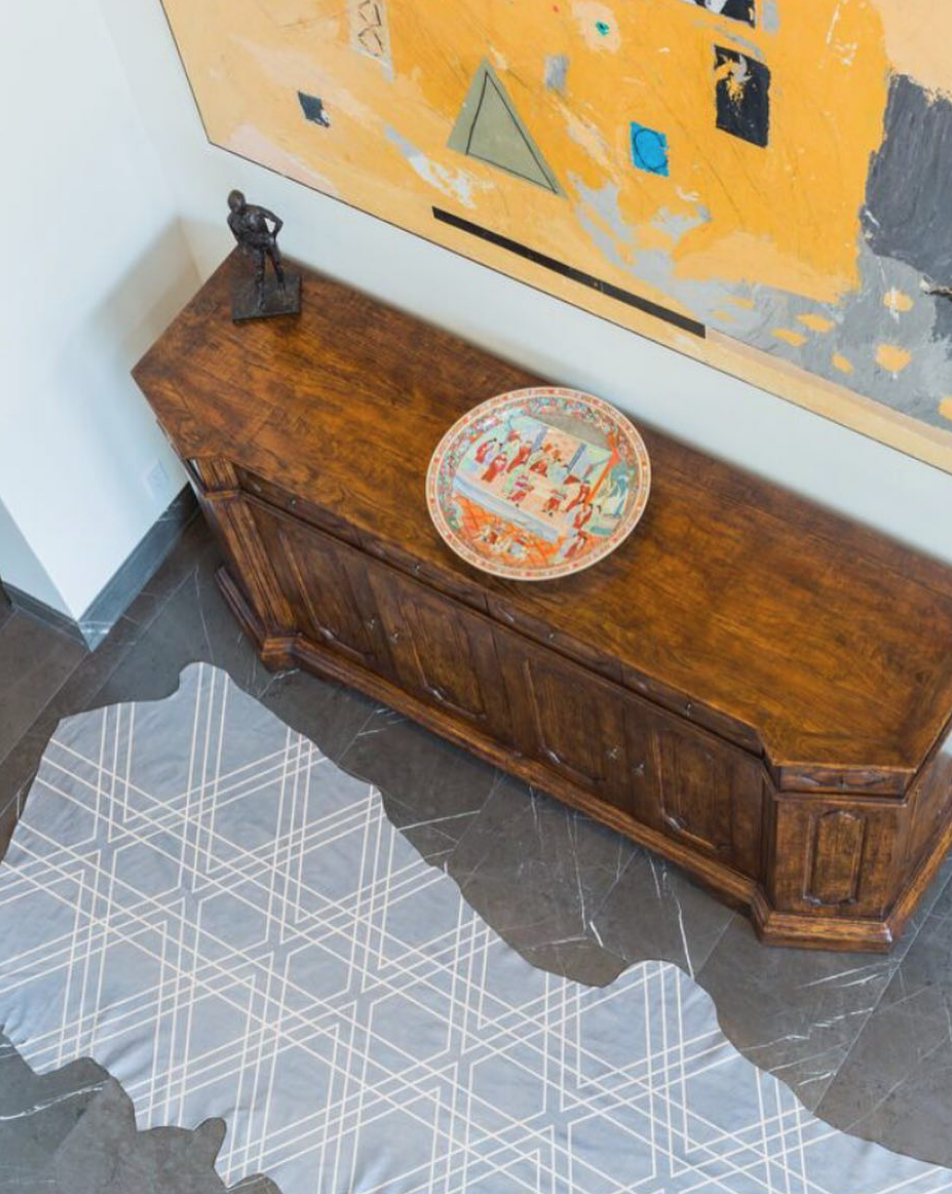 Overhead shot of a modernist living space with a cowhide rug in blue-gray with a tan geometric overlay.