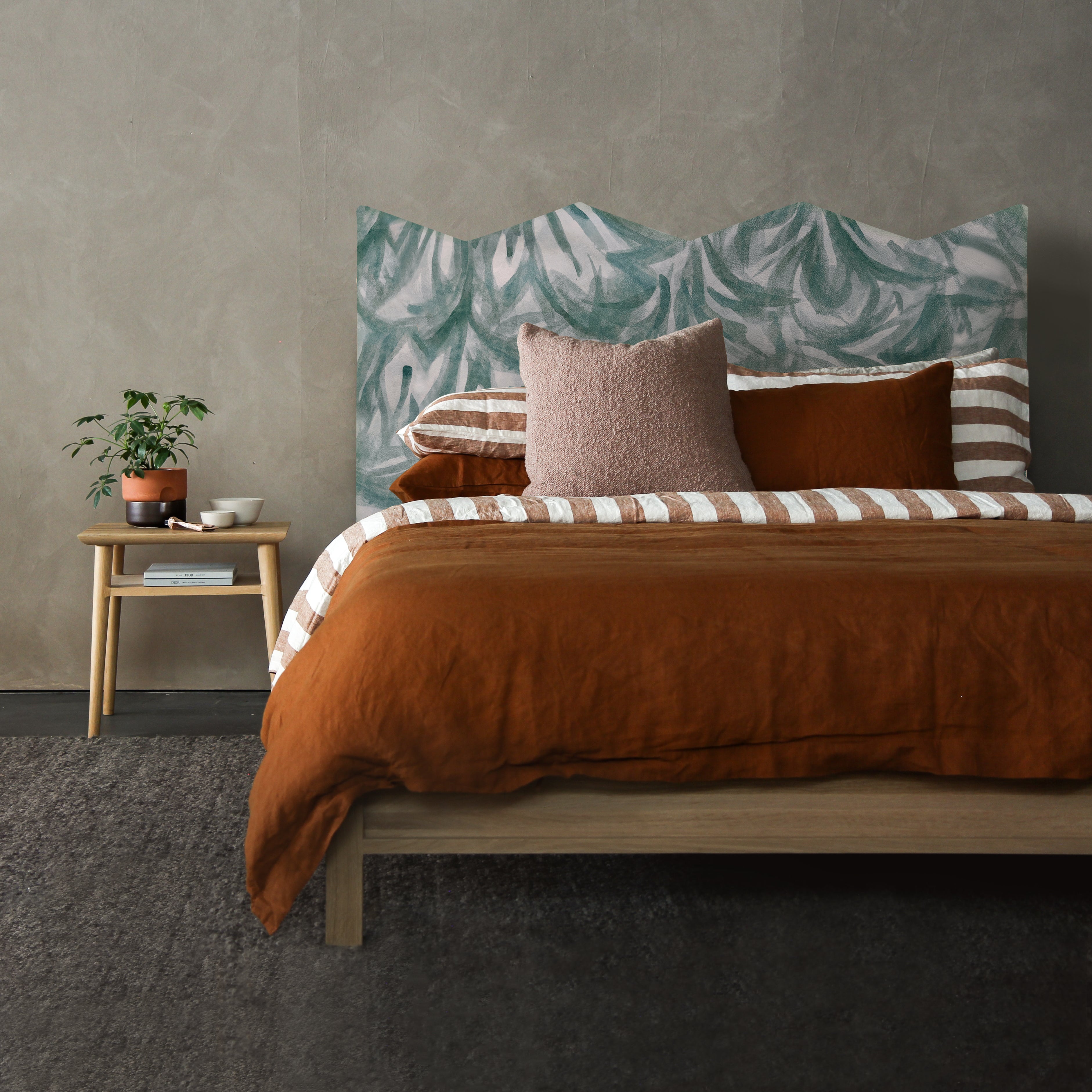 A bedroom space with a headboard upholstered pink leather with a painterly botanical overlay in green.