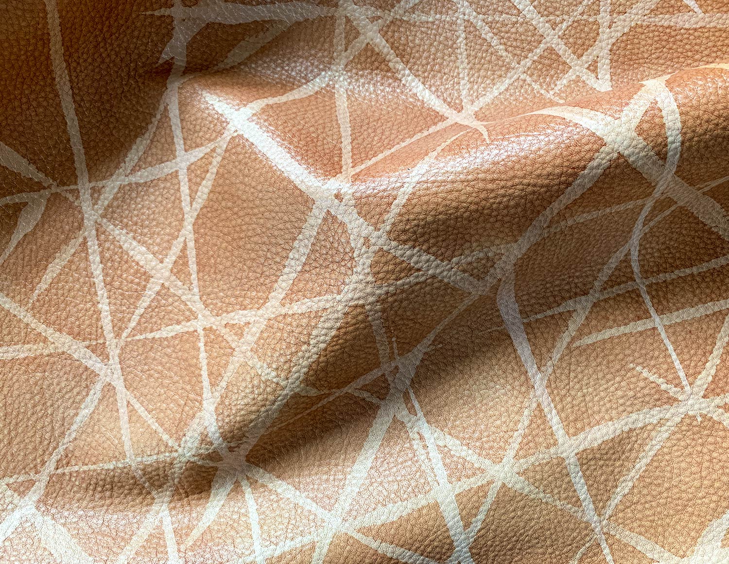 Draped upholstery leather in tan with a painterly grid overlay in white.